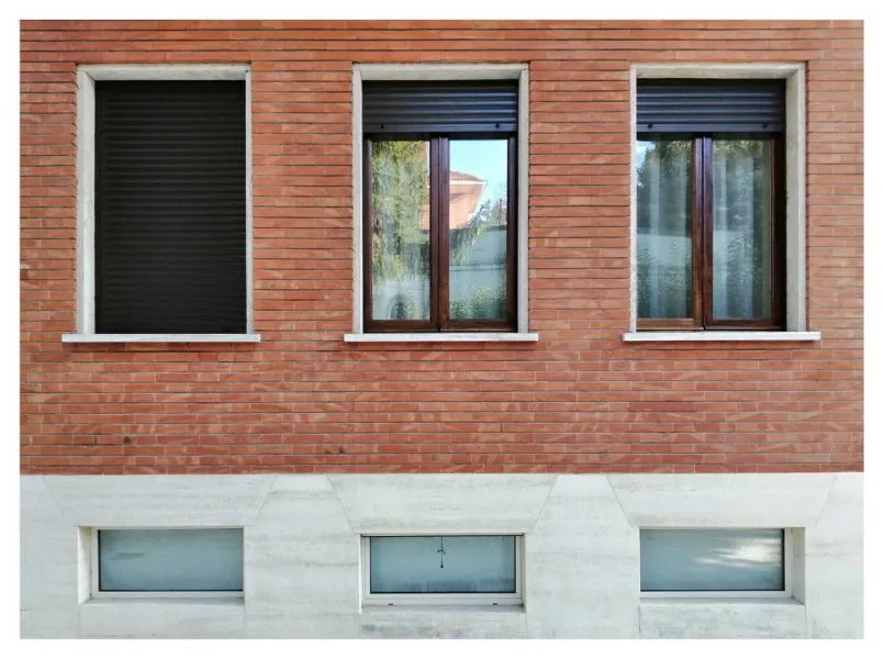 Il basamento in finto travertino, i mattoni faccia a vista e le finestre. Foto di Michela Mazzoli